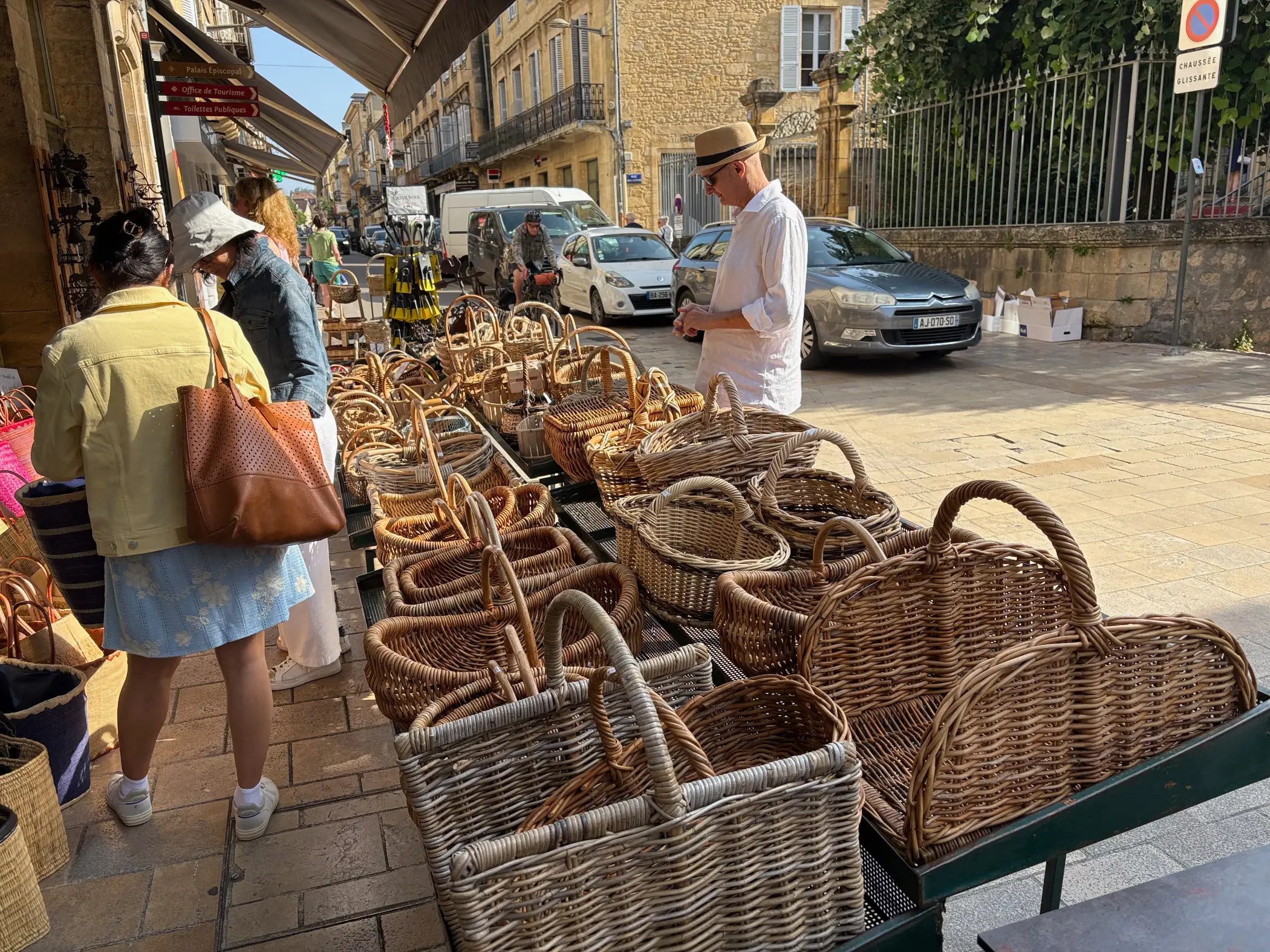 Corinne next to a row of baskets during a weekly market in the French town of Sarlat-la-Canéda